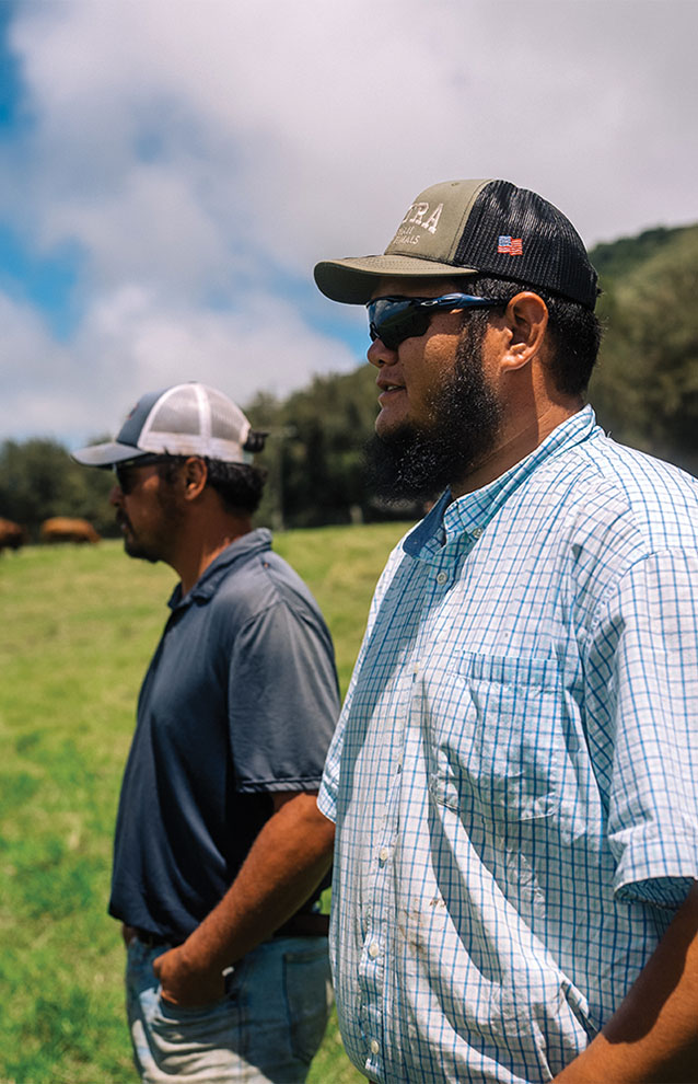 two ranch men outside with sunglasses in the green field with blue skies.